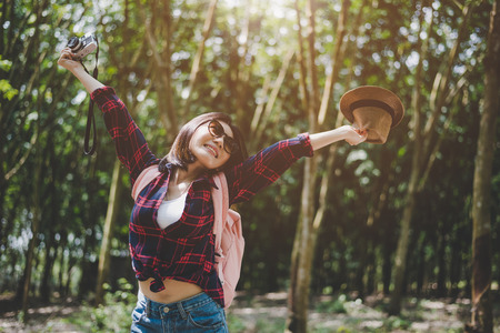 Happiness Asian traveler woman in forest with spread arms and enjoy fresh air. Relax time and Adventure concept. Vacation and Holiday concept. Woods and countryside background theme.の写真素材