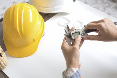 Construction engineer measuring with vernier caliper. Business and Technology concept. Safety helmet and Drawing paper elements. Civil and Drawing sketch theme.の写真素材