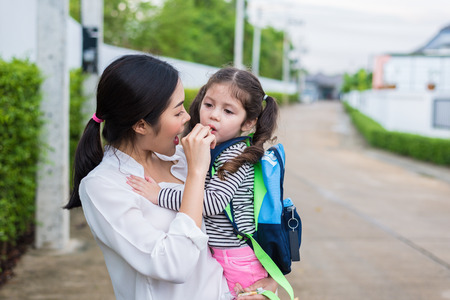 Mom feeding her daughter with snack before going to school. Back to school and Education concept. Home sweet home and happy family theme.の写真素材