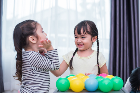 Two little girls playing small toy balls in home together. Education and Happiness lifestyle concept. Funny learning and Children development theme. Smile facesの写真素材