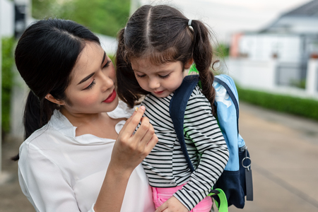Mom feeding her daughter with snack before going to school. Back to school and Education concept. Home sweet home and happy family theme.の写真素材