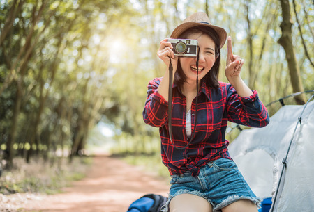 Asian beauty traveler taking photograph by digital cemera while hiking camping. Adventure and leisure activity concept. Happy life and technology theme. Solo girl theme.の写真素材