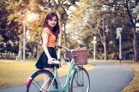 Asian woman portrait in public park with bicycle. People and Lifestyles concept. Relaxation and activity theme.の写真素材