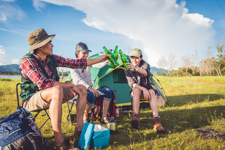 Group of travelers camping and doing picnic in meadow with tent foreground. Mountain and lake background. People and lifestyles concept. Outdoors activity and leisure theme. Backpacker and Hiker themeの写真素材