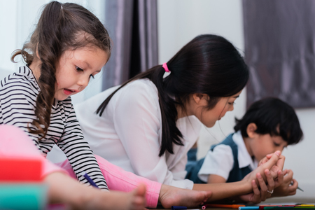 Mother teaching children in drawing class. Daughter and son painting with colorful crayon color in home. Teacher training students in art classroom. Education and Learning development of kids theme.の写真素材