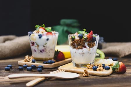 Healthy Greek yogurt with Granola and mixed berries on wooden table and many fruits. Food and dessert concept.の写真素材