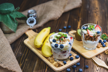 Healthy Greek yogurt with Granola and mixed berries on wooden table and many fruits. Food and dessert concept.の写真素材