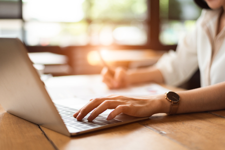 Close up of woman typing keyboard on laptop in coffee shop. People and technology concept. Freelance and Lifestyle theme. Entrepreneur and working outside office theme.の写真素材