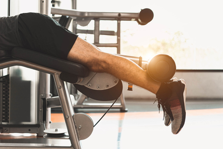 Close up of sport man stretching and lifting weight by two legs when facing down for stretching muscle at fitness gym at condominium background. Sport and People lifestyles concept.の写真素材