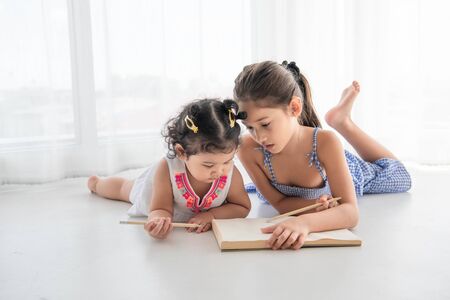 Happy two sister drawing in sketch book together at home. People lifestyle and kids play. Education...
