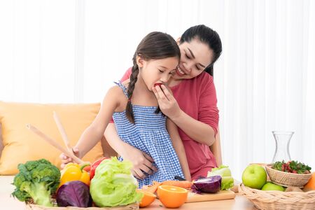 Mother and daughter cooking and eating homemade food together at home. People lifestyles and food ingredients. Health and nutrition concept.の写真素材