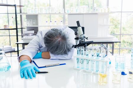Exhausted scientist sleeping in laboratory. People lifestyles and occupation concept. Science and experiment in lab theme.の写真素材