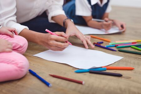 Closeup Mother and little children drawing cartoon in art class to drawing cartoon in art class with color pencil. Back to school and Education concept. Family and Home sweet home theme. Mom teachingの写真素材