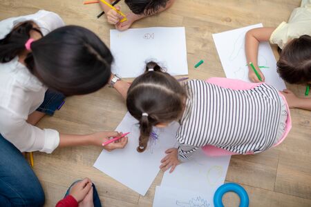 Group of preschool student and teacher drawing on paper in art class. Back to school and Education concept. People and lifestyles theme.  Room in nurseryの写真素材