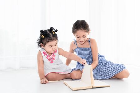 Happy two sister drawing in sketch book together at home or nursery. People lifestyle and kids play. Education and Children concept. Diverse ethnicity and ages. Back to school themeの写真素材