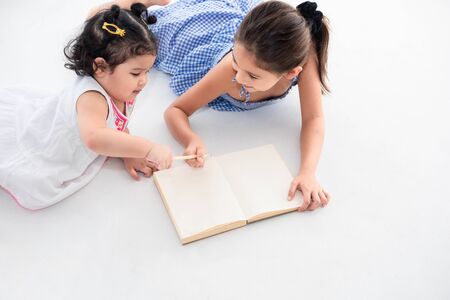 Top view of happy two sister drawing in sketch book together at home or nursery. People lifestyle and kids play. Education and Children concept. Diverse ethnicity and ages. Back to school themeの写真素材