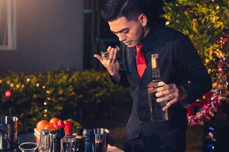 Professional bartender preparing fresh lime lemonade cocktail in drinking wine glass with ice at night bar clubbing counter. Occupation and people lifestyles concept. Outdoor backgroundの写真素材