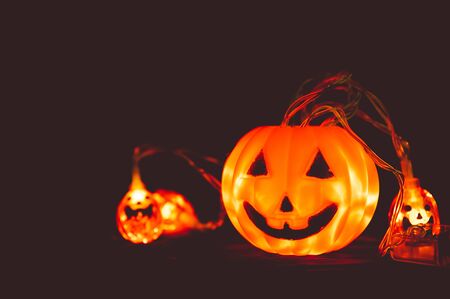 Halloween pumpkin and light in dark, wooden background. Halloween festival celebration concept. Low key toned. Copy spaceの写真素材