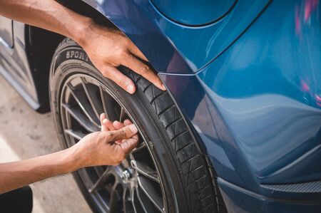 Closeup male automotive technician removing tire valve nitrogen cap for tire inflation service at garage or gas station. Car annual maintenance and repair concept. Safety road trip and travel theme.の写真素材