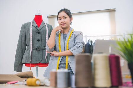 Fashion designer stylist in business owner workshop. Tailor and sewing concept. Portrait of happy casual trendy fashion designer businesswoman in studio looking camera. Business job and occupationの写真素材