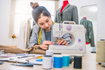 Attractive female fashion designer hand working in workshop with sewing machine. Stylish fashionista woman creating new cloth design collection. Tailoring and sewing Lifestyle and business occupationの写真素材