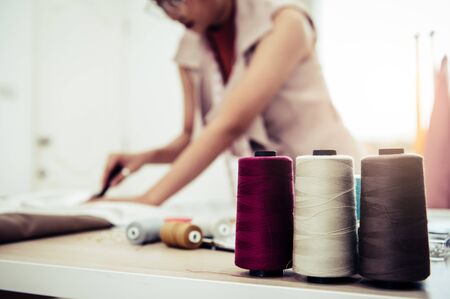 Closeup of colorful thread with fashion designer background in workshop studio. Stylish fashionista woman creating new cloth design collection. Tailoring and sewing People lifestyle and occupationの写真素材