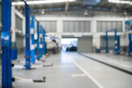 Blurred background of repairing garage with no people. blurry mechanics workshop car station and vehicle fixing and lifted automobile in service centerの写真素材