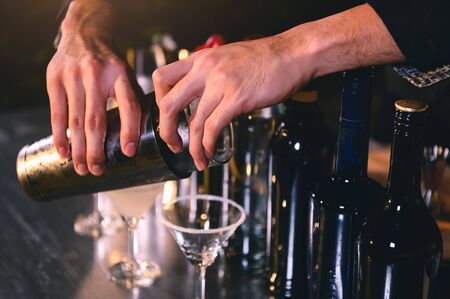 Closeup bartender hand preparing fresh juice cocktail in drinking wine glass with ice at night bar clubbing counter. Occupation and people lifestyles concept. Outdoor and nightclub backgroundの写真素材