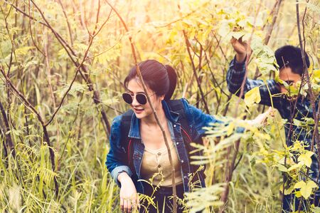 Group of Asian friendship adventure in forest jungle view background. Girl leading tourism team in nature. People lifestyle travel on vacation concept. Summer picnic and camping. Trekking hikingの写真素材
