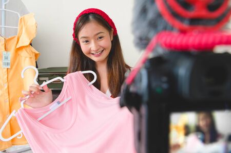 Beauty young Asian Vlogger blogger interview with professional DSLR digital camera film video live. Woman coach trading review clothing product. Business presentation training class. People lifestyleの写真素材