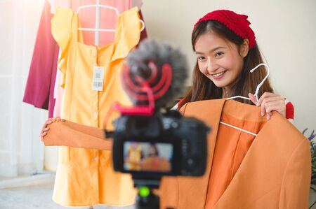 Beauty young Asian Vlogger blogger interview with professional DSLR digital camera film video live. Woman coach trading review clothing product. Business presentation training class. People lifestyleの写真素材
