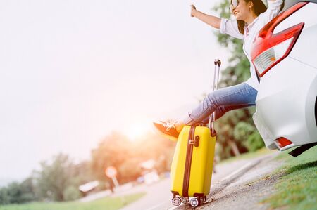 Happy Asian woman spread arms widely and breathed fresh air with happiness mood in on raod trip in car trunk. People lifestyle in long vacation trip concept. Outdoors nature and transportationの写真素材