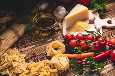 Tasty appetizing italian spaghetti pasta ingredients for kitchen cuisine with tomato, cheese parmesan, olive oil, fettuccine and basil on wooden brown table. Food Italian recipe homemade. Top viewの写真素材