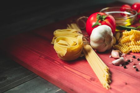 Tasty appetizing italian spaghetti pasta ingredients for kitchen cuisine with tomato, cheese parmesan, olive oil, fettuccine and basil on wooden brown table. Food Italian recipe homemade. Top viewの写真素材