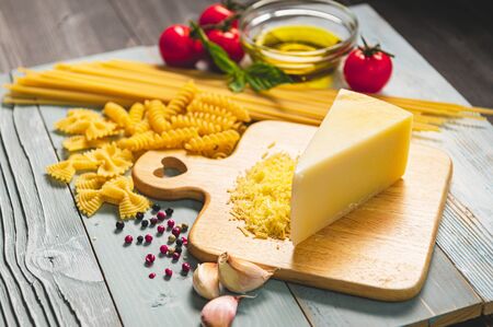 Tasty appetizing italian spaghetti pasta ingredients for kitchen cuisine with tomato, cheese parmesan, olive oil, fettuccine and basil on wooden brown table. Food Italian recipe homemade. Top viewの写真素材