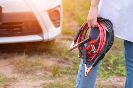 Closeup of woman hand holding battery cable copper wire for repairing broken car by connect battery...