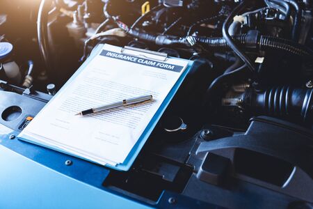 Clipboard on car with car insurance claim form for customer maintenance vehicle checklist in auto repair shop garage. Engine repair service concept. Business technical mechanics support for fixing carの写真素材