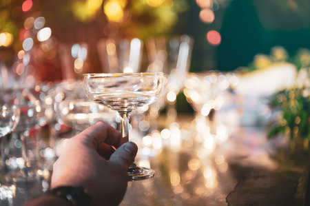 Closeup hand holding martini wine glasses on outdoors counter bar in the garden at night for celebration party.の写真素材