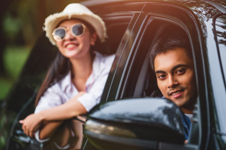 Happy Asian man looking outside open window car with his girlfriend on forest background. People...