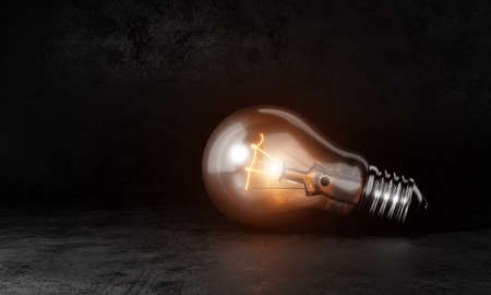 Light bulb with orange warm white light in dark room background and copy space. Conceptual and...