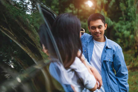 Asian man talking to women in car during travel in forest. Boy flirting girls for meeting. People lifestyles and weekend tour concept. Summer and nature theme. Mountain camping people group in holidayの写真素材