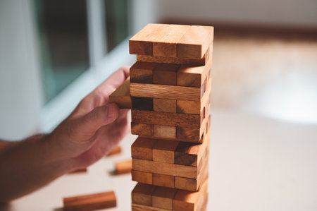 Wooden blocks toy puzzle with human hand on table at home background. Entertainment and business concept.の写真素材