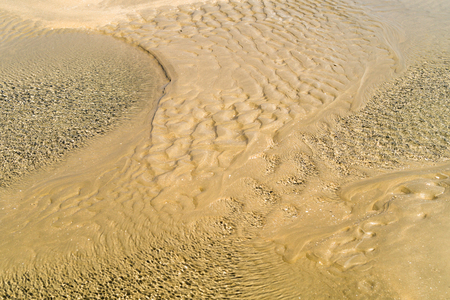Low tide sand and water ripples on the beach .