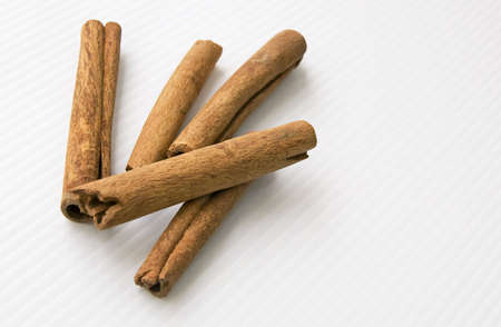 Cinnamon sticks on a white linear textured tabletop.