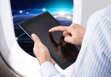 Businessman holding digital tablet in airplane with horizon backgroundの写真素材