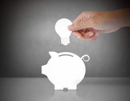 Male hand putting light bulb into a piggy bank, idea conceptの写真素材