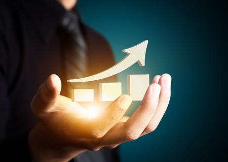 Hand holding a rising arrow, representing business growth.の写真素材