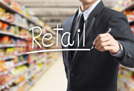 Business man writing word retail in the supermarketの写真素材