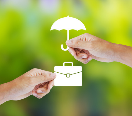 Business insurance concept with an umbrella covering business briefcaseの写真素材