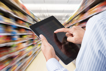 Businessman checking inventory in supermarket on touchscreen tablet. Motion blur Backgroundの写真素材